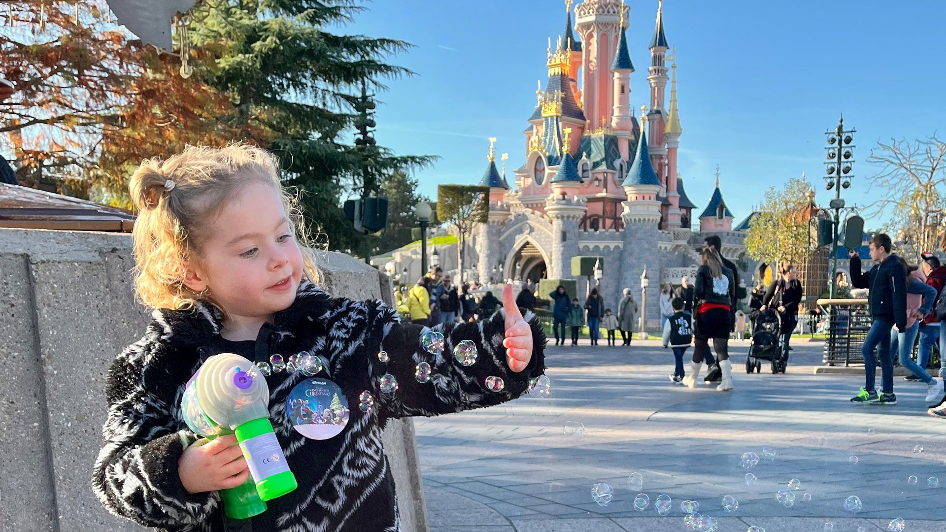 Lola vermaakt zich met een elektrische bellenblazer, een typisch souvenir, voor het kasteel in Disneyland.