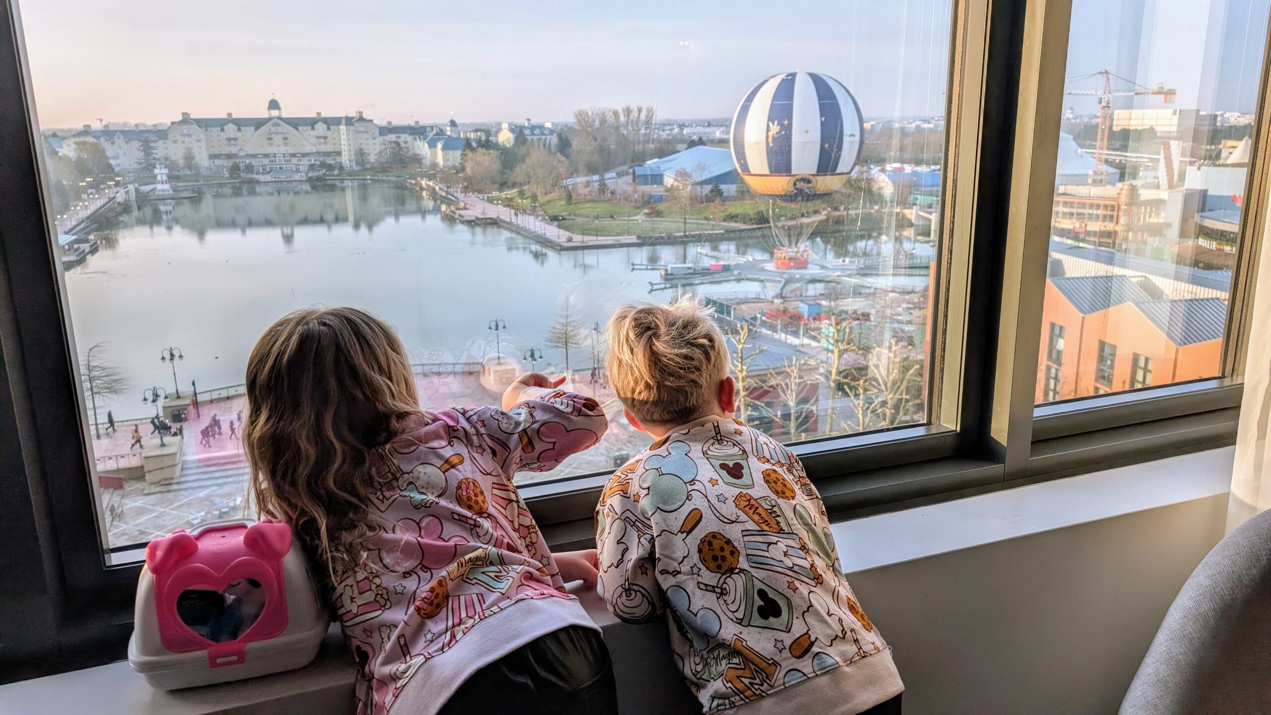 Lola en Jimmy kijken vanuit onze Empire State Club kamer over Lake Disney naar de luchtballon