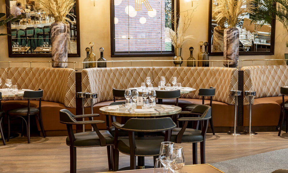 De sfeervol verlichte ingang en het terras van Brasserie Rosalie in Disney Village bij schemering.